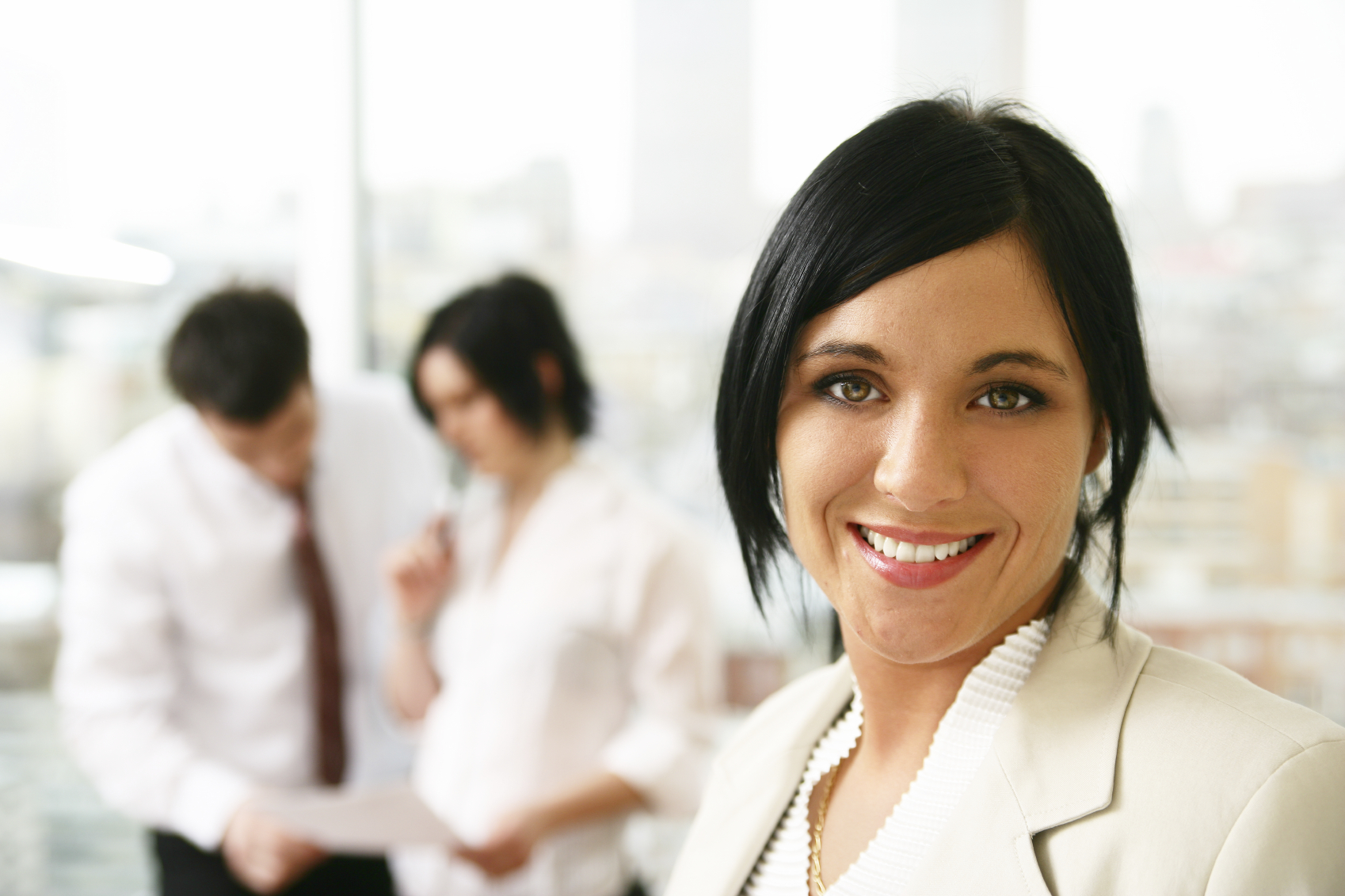 Photo of a live agent posing in front of two staff members discussing a document.